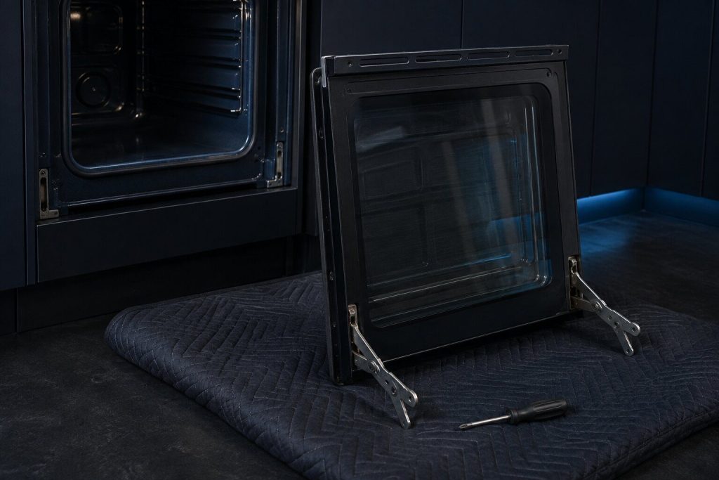 An oven door off and lying on a blanket with its hinges locked open